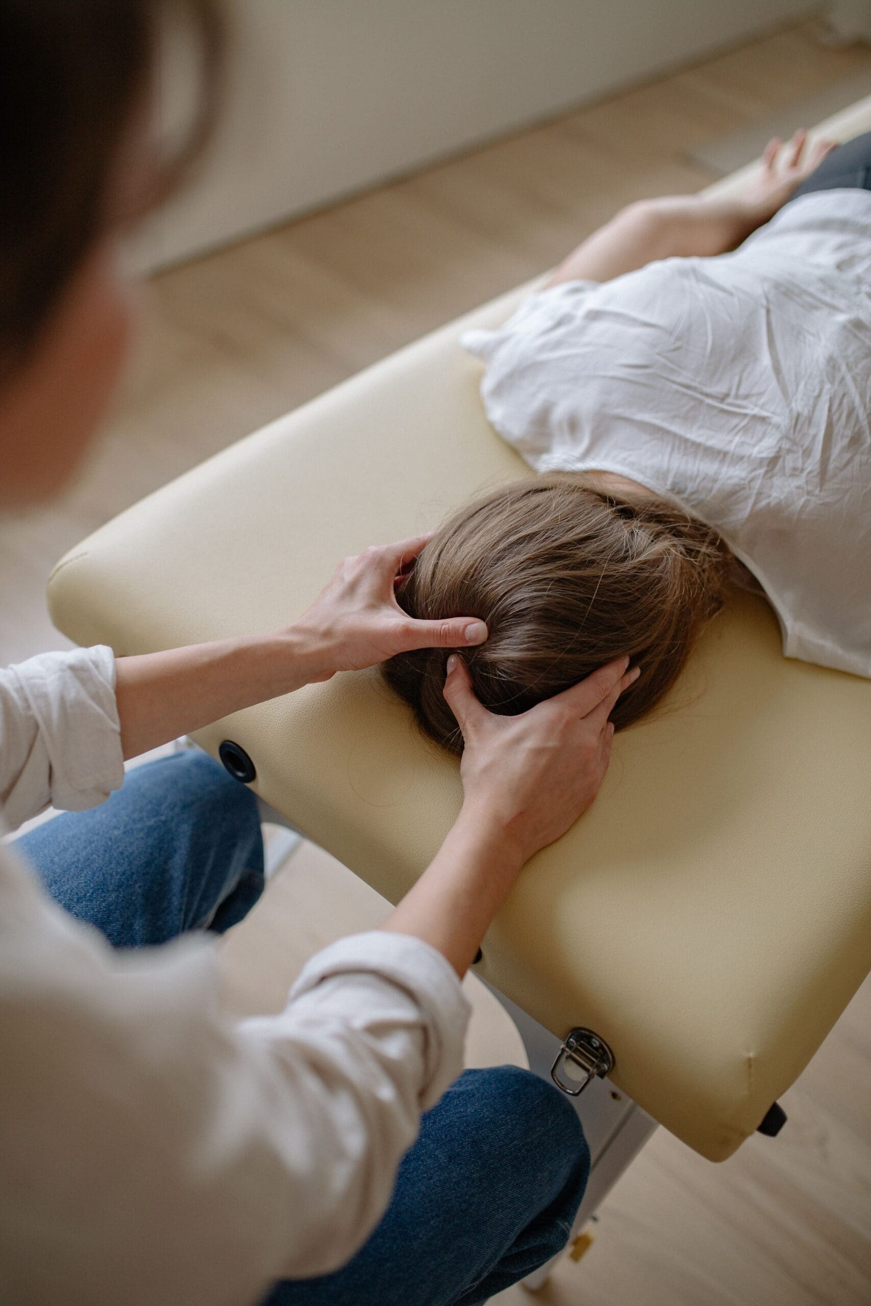 A woman laying on a chiropractic table with a practitioner doing work on her head.